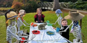 childresn and plastic skeletons sitting around a table pretending to have tea