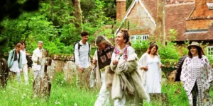 a group of musicians smiling, walking through a churchyard enchanting forest
