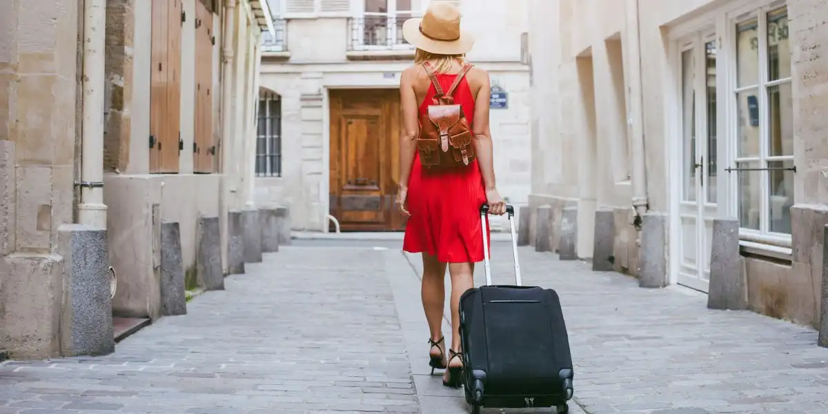 packing for city break woman walking down a cobbled street with a wheelie case