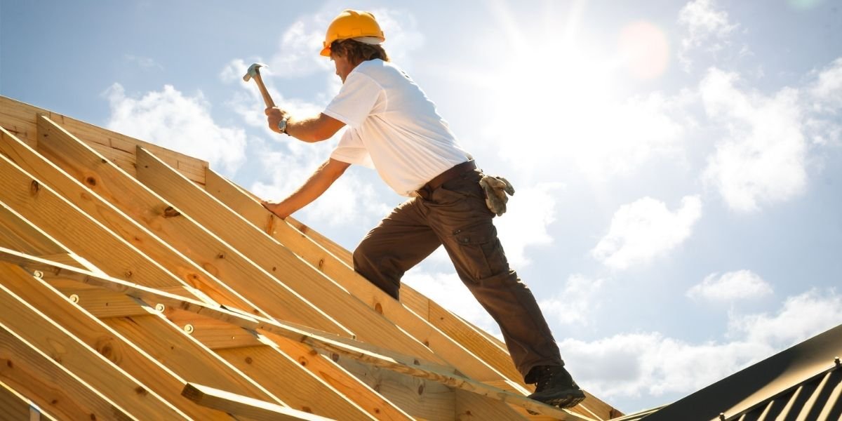 a man on a timber roof holding a hammer house renovation