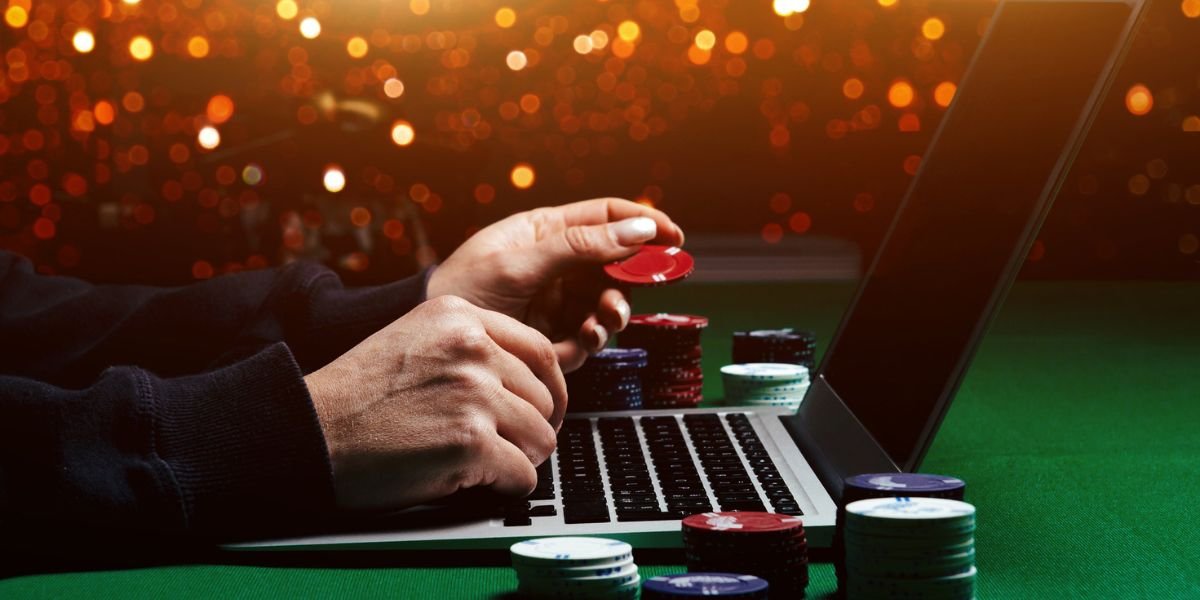 a laptop on green baize with hands holding casino chips - protect data online casino