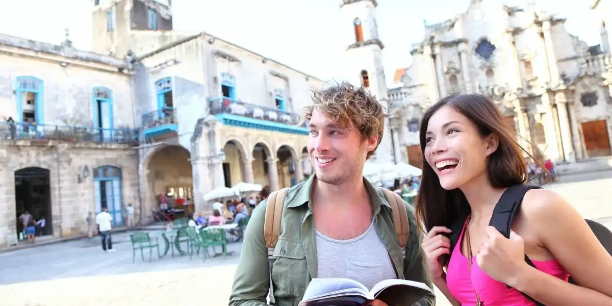 Young multiracial happy couple on gap year standing on Plaza de la Catedral, Old Havana.