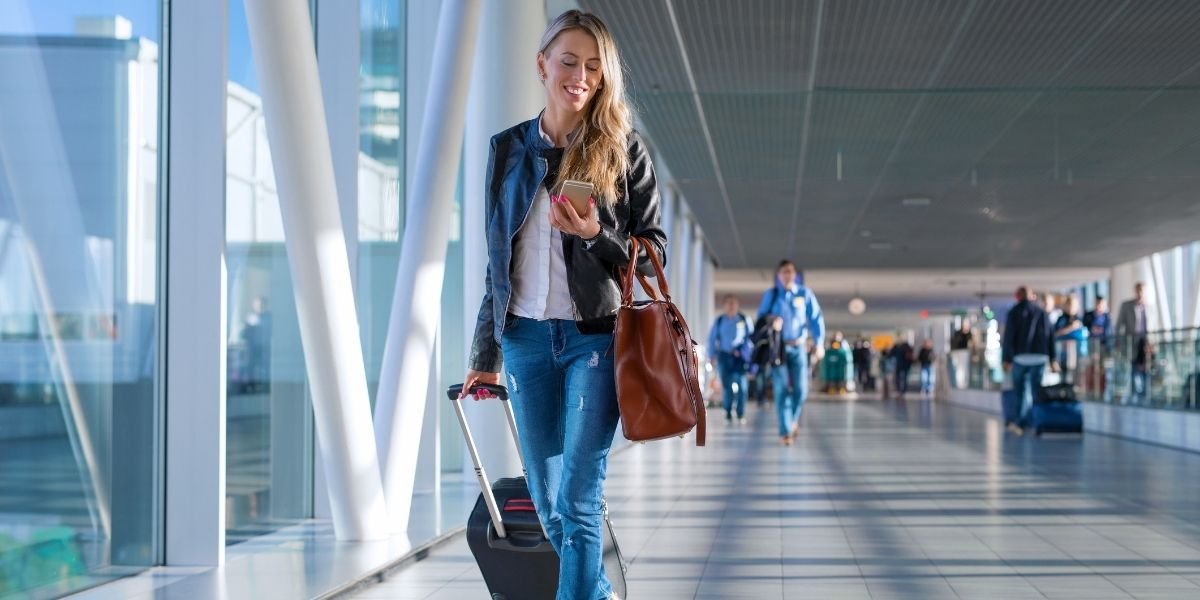 woman walking through an airport enjoying a game on her phone