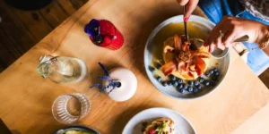 brunch in york womans hands cutting into a stack of pancakes