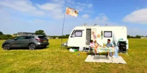 Caravan parked up with 30 something couple and small child eating outside