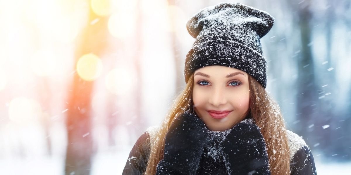 woman with woolly hat smiling and dusted with snow