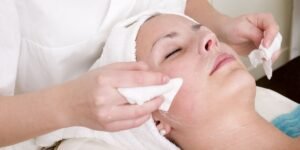 woman in skincare clinic having product removed with cotton pads