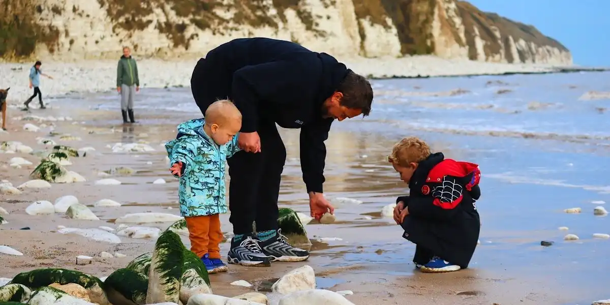 man and two children on the beach at flamborough collecting stones