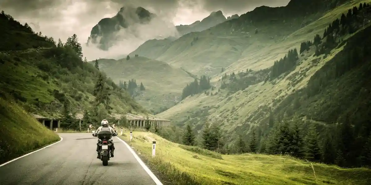Motorcyclist on mountainous highway, cold overcast weather, Europe, Austria, Alps, extreme sport, active lifestyle, adventure touring concept. Making the Most of Your Travels