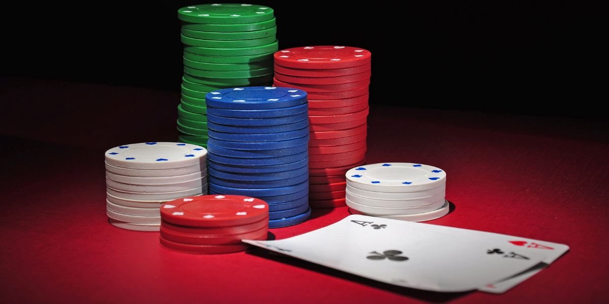 a stack of casino chips on a black and red background with playing cards in the foreground