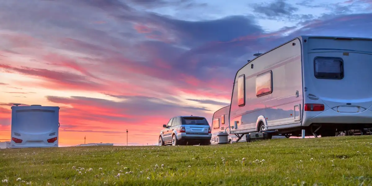 Camping caravans and cars sunset. Camping caravans and cars parked on a grassy campground under beautiful sunset