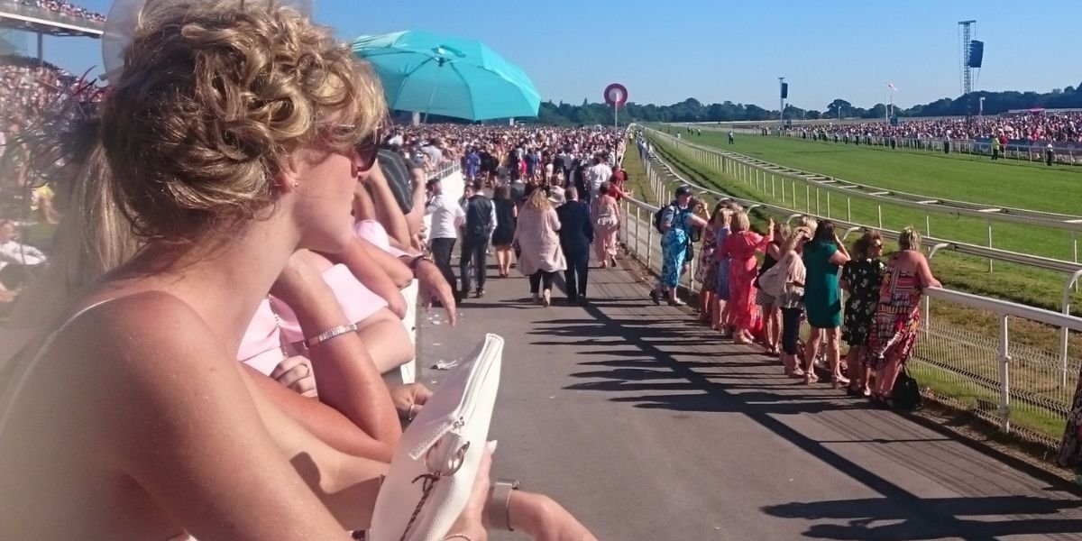 a woman at the racecourse with the horse race track in front of her