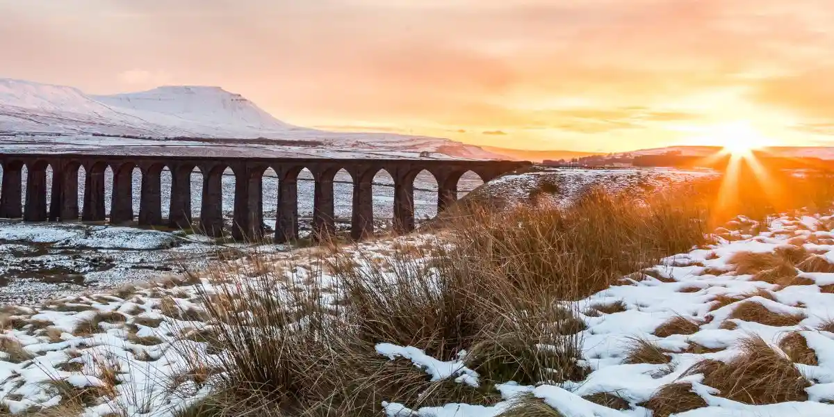 Sunset over the Ribblehead viaduct in early November snow looking towards Ingleborough. Yorkshire Dales, UK.