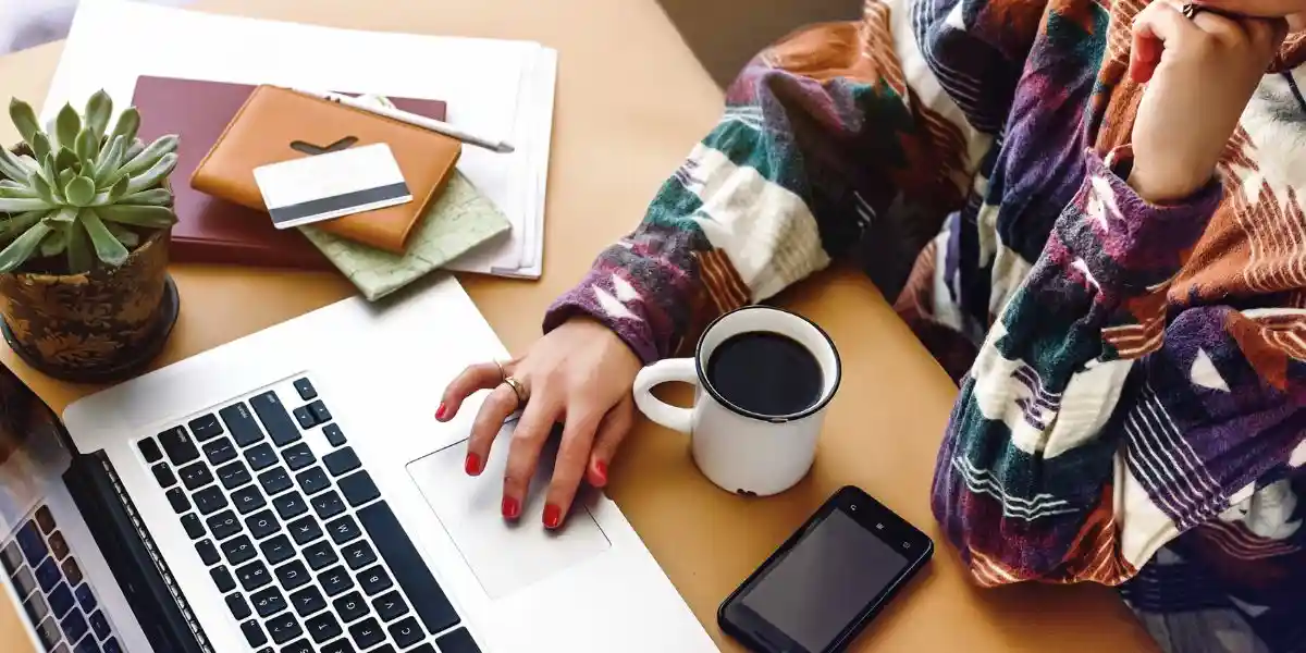 hands on laptop searching and typing, freelance and planning boho summer travel vacation concept