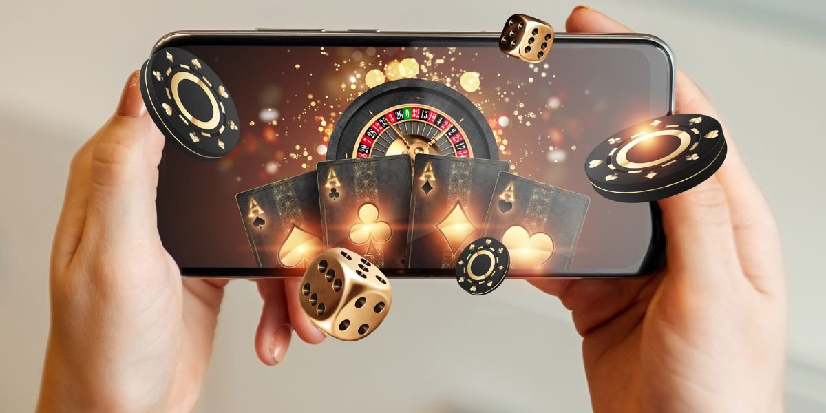 a smartphone with playing cards, roulette and chips, black-gold background. Internet gambling concept.