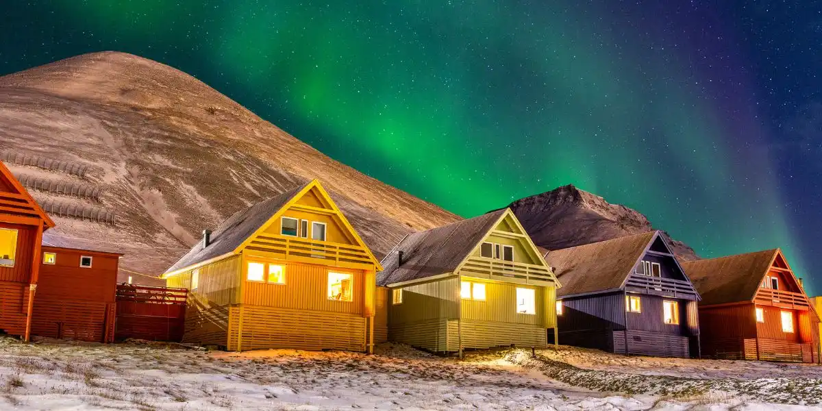 Longyearbyen colourful houses with Aurora Borealis in the sky full of stars.