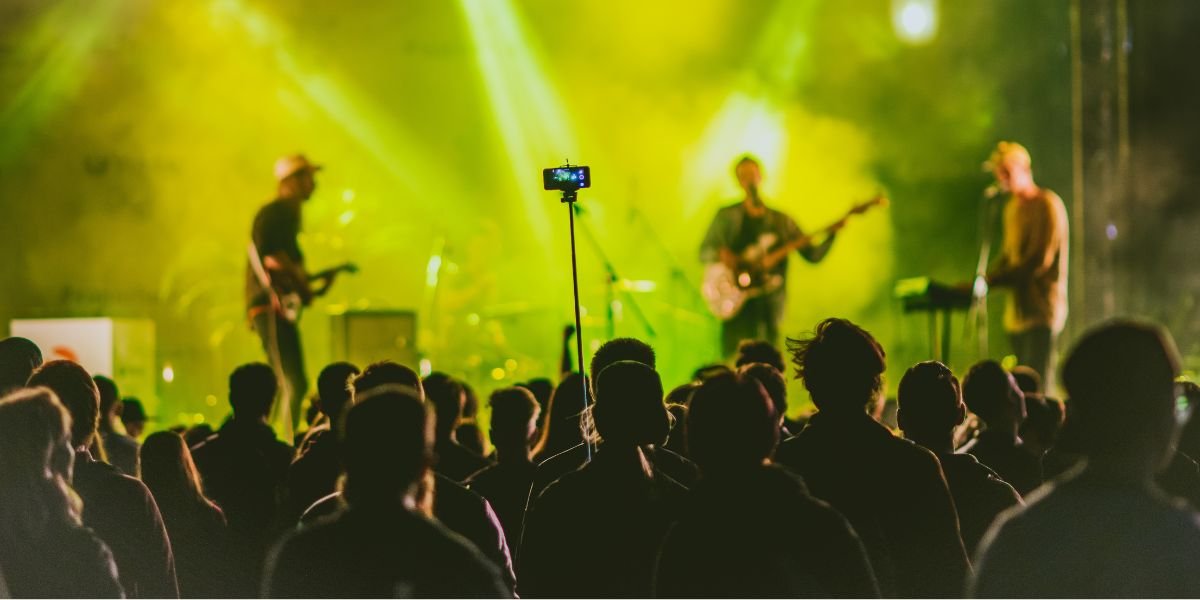 Person capturing a video on a mobile phone with selfie stick at a music festival Raw lo fi video