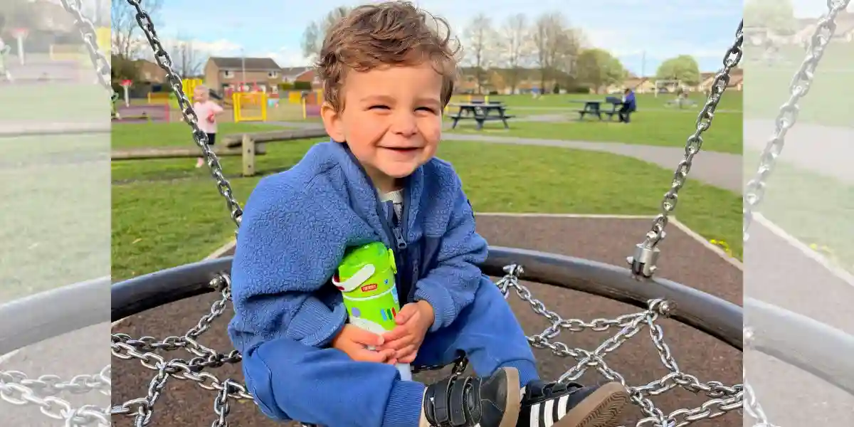 young boy laughing sitting in a playground