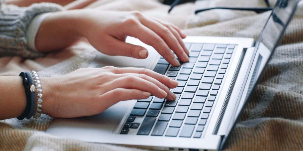 Female hands type on laptop, checking a licence online