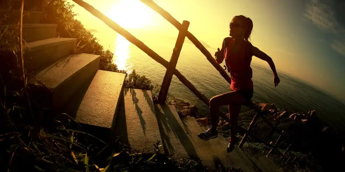 a woman running up a mountain at sunset