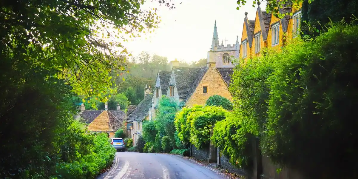 A picturesque country road lined with quaint houses and trees. Cotswolds, a peaceful village in UK