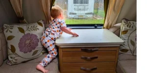 young child looking out of the window of a caravan