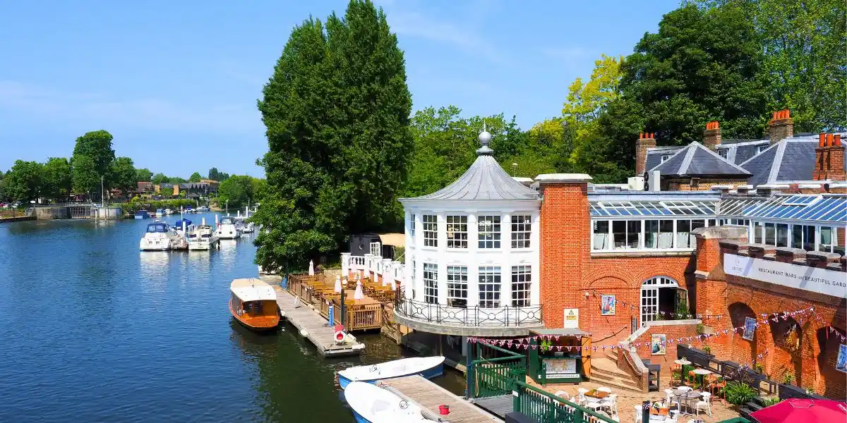 The River Thames at Hampton Court in London. Hire boats and the attractive town of Hampton on the River Thames in England