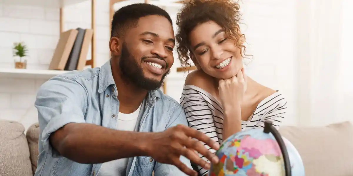couple with globe choosing place for travel. African-american couple dreaming of travel, looking at globe and choosing place for vacation