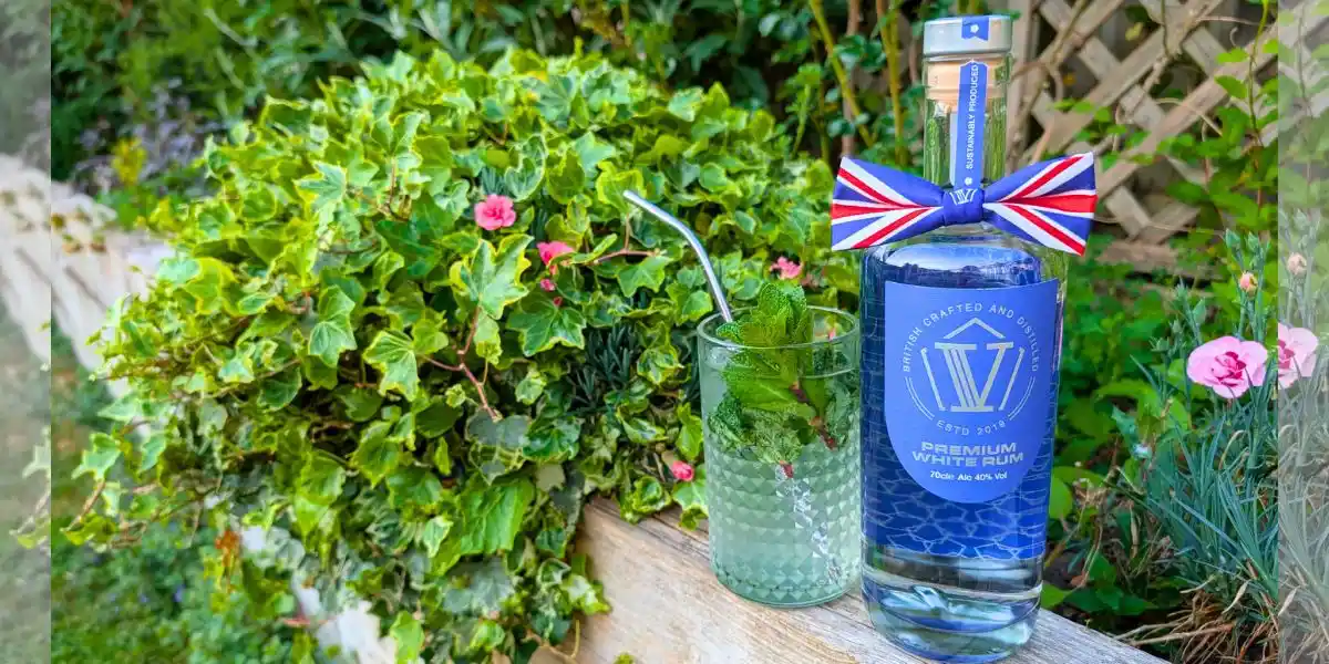 bottle of v rum in a garden summer setting red white and blue ribbon