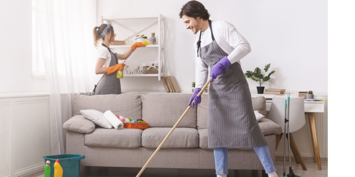 Couple Of Skilled Housekeepers Tidying Up Apartment. Couple Of Skilled Housekeepers Man And Woman Tidying Up Apartment Airbnb cleaning services