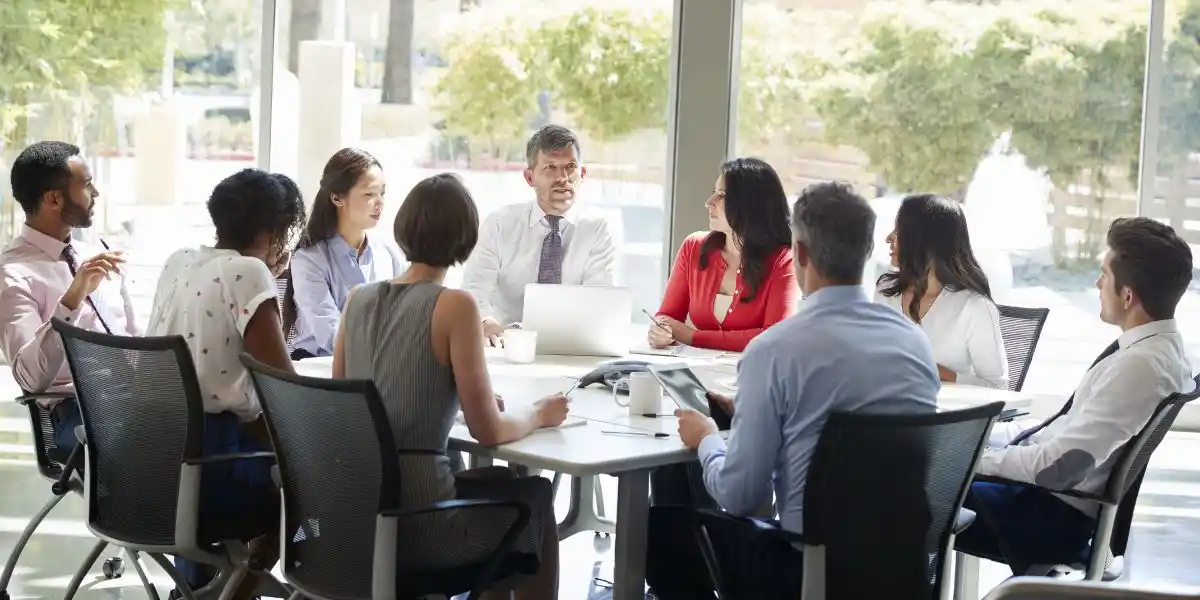Corporate business team in discussion in a bright meeting room that needs blinds