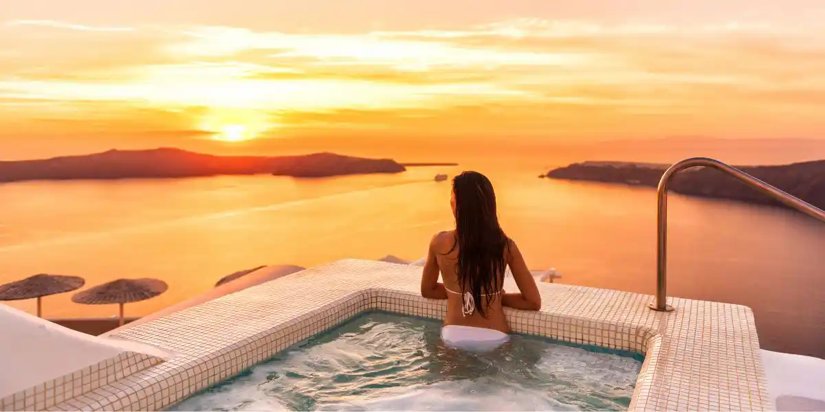 woman sitting in a pool looking at a med sunset