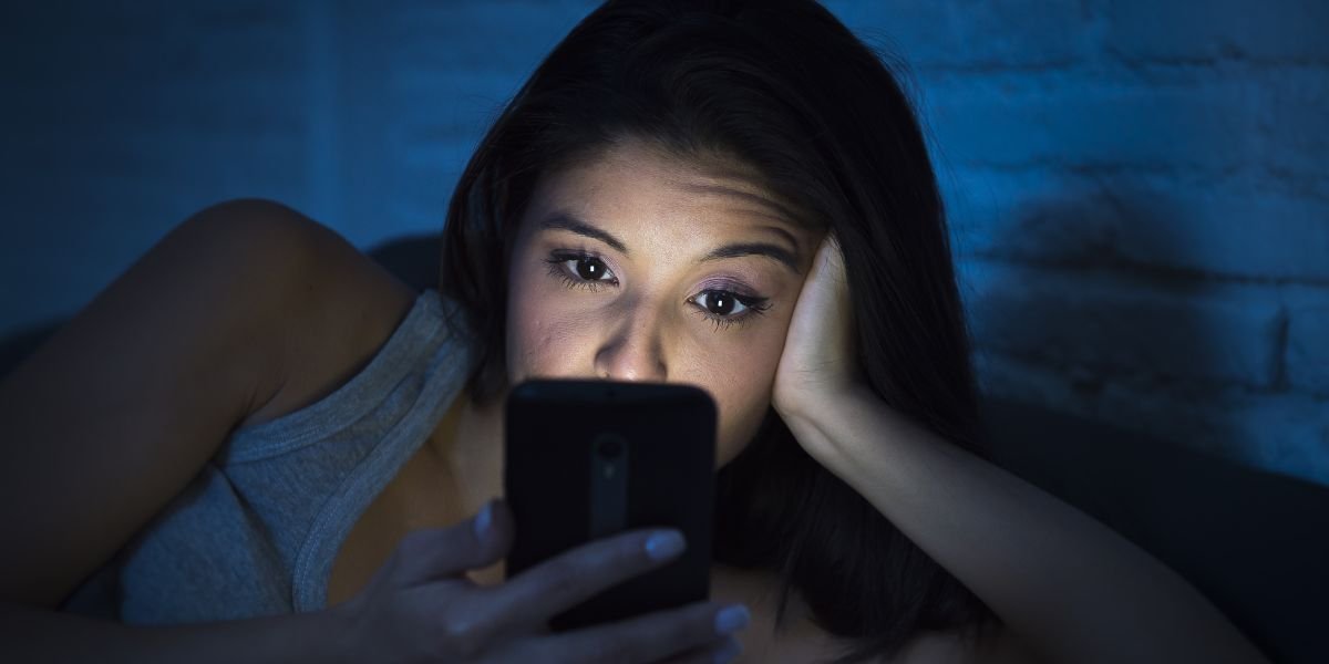 woman in hotel bed using mobile phone late at night at dark bedroom. app for travelling