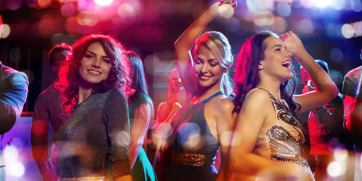 Party, holidays, celebration, nightlife and people concept - happy friends dancing in club with lights