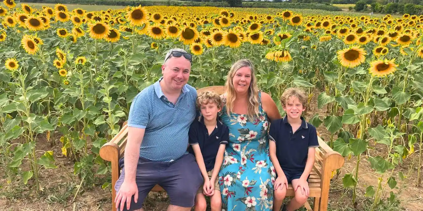 A family sitting on a bench in front of a field of sunflowers at Castel Farm in Kent