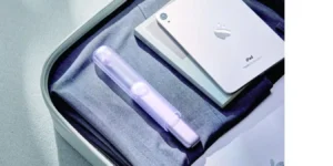 a travel toothbrush in a toiletry bag with other travel tech close by