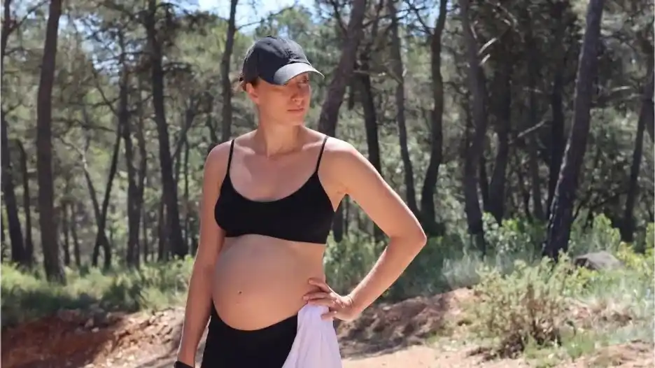 a pregnant woman on a hike in the sunshine