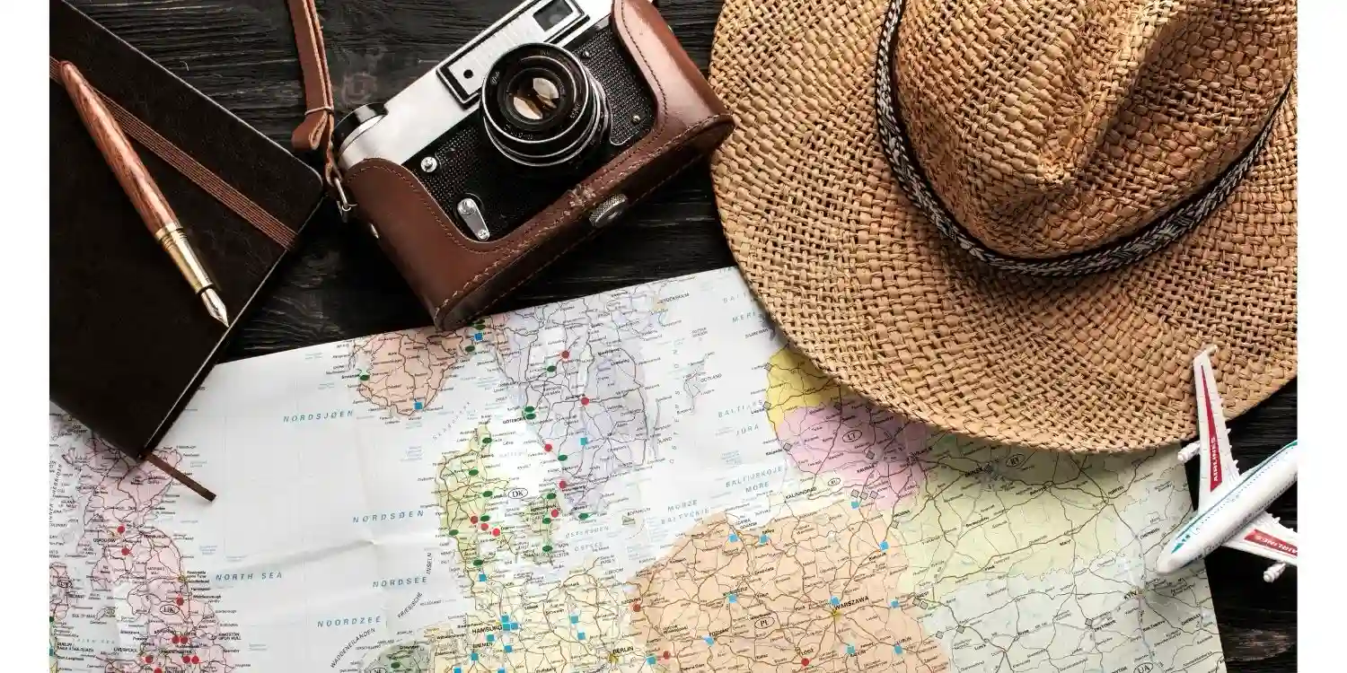 Frugal Travel concept choosing to spend less to go on holiday. a map camera and sunhat