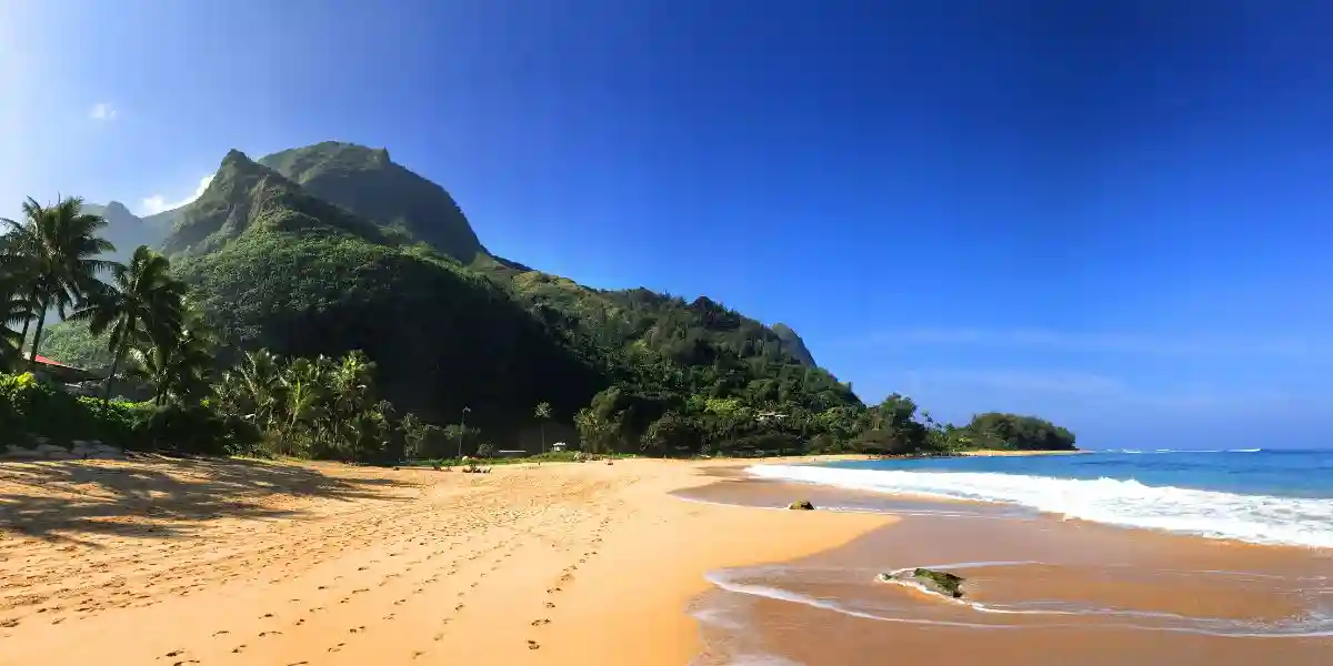 The golden sands and green lush mountains of Tunnels Beach in Kauai Hawaii