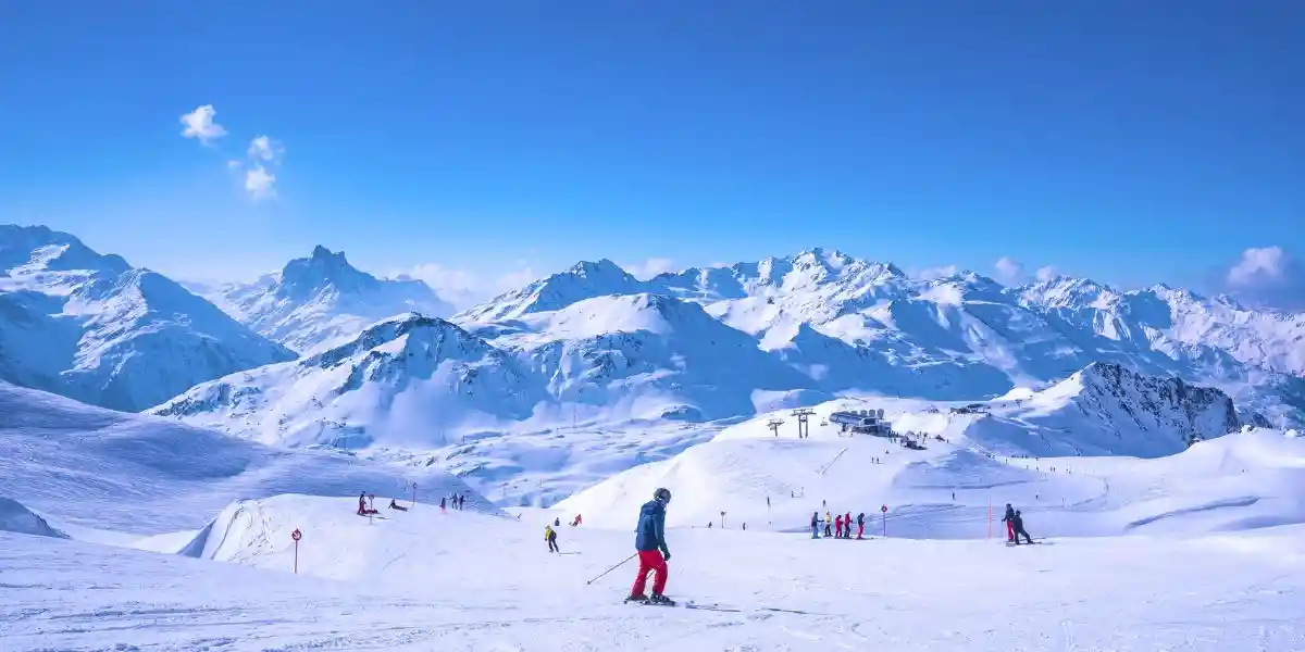 Skiers sliding down snowy slope on mountain at winter resort. St. Anton am Arlberg.