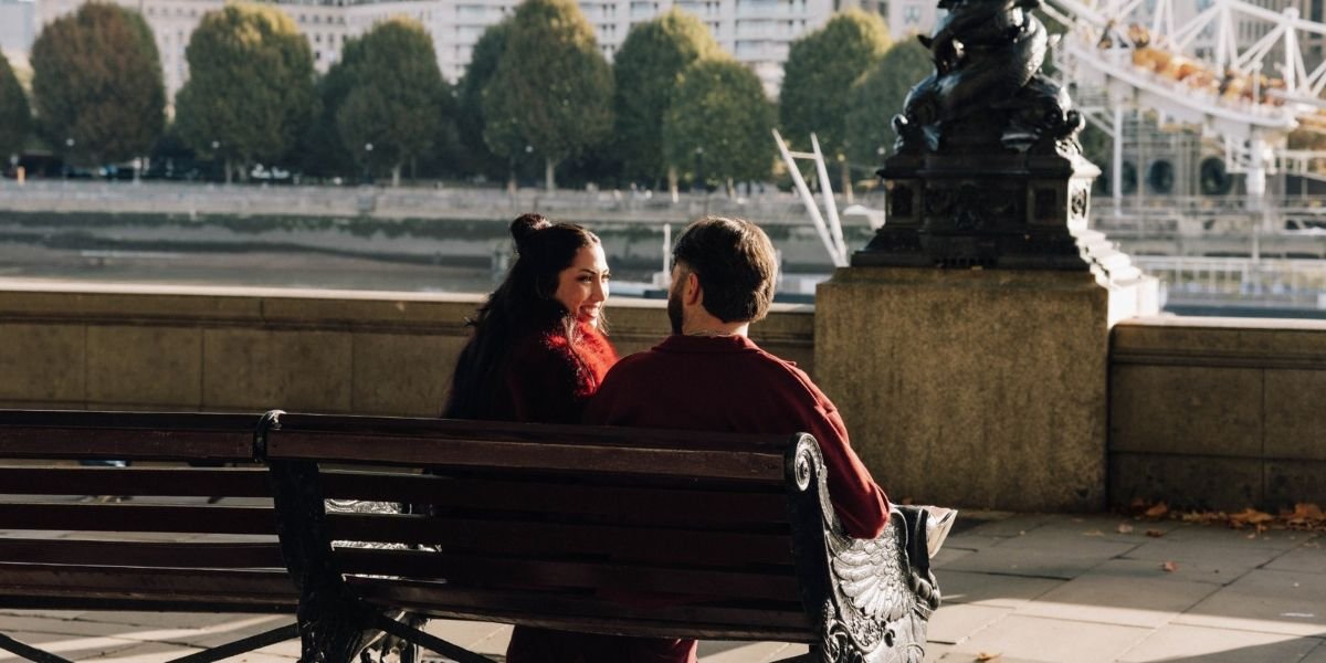 couple sitting on a bench in London opposite the london eye