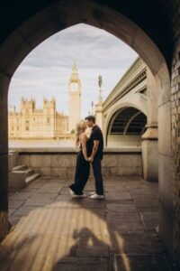 Couple kissing in the stone arch under Westminster Bridge on the South Bank, Big Ben and Parliament framed behind